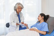 © M+Isolation+Photo - An elderly Asian doctor with a stethoscope is checking young Asian patient in hospital bed, take history of illness Health check and encouragement