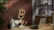Portrait of female in cardboard box with emoji on head. Worker at the desk holding smartphone and credit card typing number.