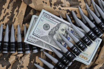 Bundles of dollars and a machine gun belt on the camouflage uniform of a Ukrainian soldier. Concept of war financing, bribe or donation. Help to Ukraine from the USA