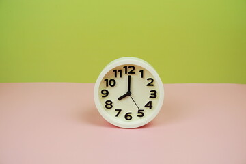 Canvas Print - White alarm clock with space copy on green and pink background