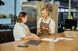 © LIGHTFIELD STUDIOS - smiling cafe administrator talking to young woman with down syndrome near laptop and pizza boxes