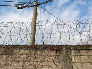 Walls, barbed wire, electric poles, electric lines, blue sky,