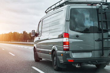 Concept of traveling with a van and enjoying the outdoor adventures. The ultimate van camping in Europe. Offroad modern van for traveling with a ladder on the back and an additional baggage roof rack.