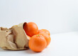 Group of tangerines in kraft paper bag.