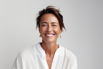 Portrait of a happy young woman smiling at camera against grey background