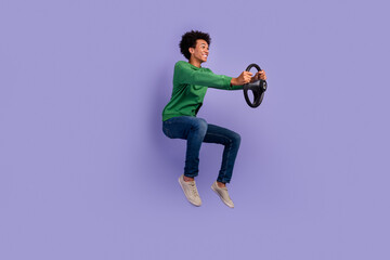 Wall Mural - Full length photo of funky good mood man dressed green sweater driving auto jumping high empty space isolated violet color background