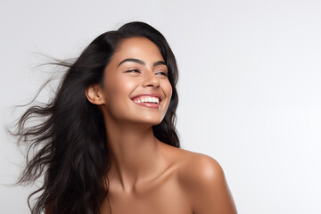 Poster - Beautiful laughing young Indian woman takes care of her skin, posing over grey background