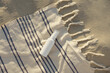 White mockup tube of cream or serum for moisturizing skin on a beach towel with a bag near the sand. The concept of sunscreens for skin, natural cosmetics and beauty