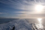 Fototapeta  - Sufrace of ocean with wake, during cruise ship. Blue sky with clouds ans sun shine.