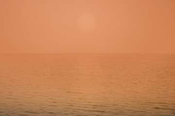 Wall Mural - Hazy sunset seascape in soft peach pastel colors for ocean tropical backgrounds