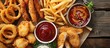 Vertical top-view image of pub appetizers with fried mozzarella sticks, onion rings, fries, chicken nuggets, and sauce; text space available.