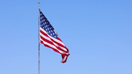 Wall Mural - us flag on a flagpole blowing in the breeze.