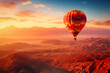 © Dmitry Rukhlenko - A colorful hot air balloon floats in sky over a desert mountain landscape at sunset with orange and blue skies in the background. Travel journey adventure beauty of nature concept