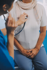 Wall Mural - Close up of Female Doctor using stethoscope putting beat heart diagnose with patient in examination room at a hospital, check-up body, Medical and Health Care Concept.