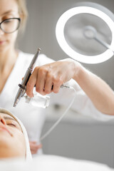 young cosmetologist performs oxygen mesotherapy on woman's face at beauty salon. concept of non-inva