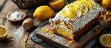 Fototapeta  - Classic lemon loaf cake on a wooden board garnished with frosting and lemon shavings Fast and tasty dessert. Creative Banner. Copyspace image