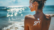 © ALL YOU NEED studio - 'spf' written with white cream on the tanned skin of the back of a girl in a swimsuit on the beach