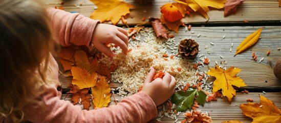 Poster - Child hands creating autumn tree with colored rice and natural materials Toddler filled the leaves with yellow and orange rice Montessori material Sensory play and fall nature crafts. Creative Banner