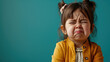 Portrait of sad offended crying little girl child on flat blue color background with copy space, banner template. A sad child makes a grimace.