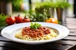 bolognese with spaghetti on a wooden table. soft background with summer vegetables and salad