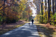 © kmm7553 - A dog walker on a paved hiking trail in autumn