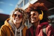 © familymedia - Two women in ear headphones talking to each other outside