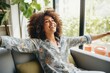 © Maksymiv Iurii - African woman celebrating a new job while sitting at home on a couch