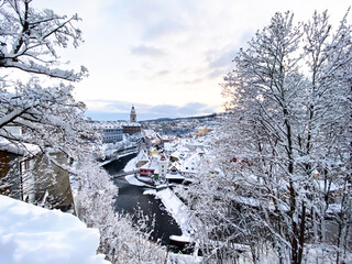 Wall Mural - Winter view of Czech Krumlov. Český Krumlov, UNESCO. Historical town with Castle and Church at sunrise. Beautiful winter morning landscape with an illuminated monument. Snowy cityscape scene from the 