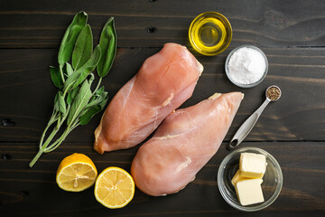 Wall Mural - Chicken Breasts with Fresh Sage Ingredients: Chicken breasts, sage sprigs, fresh lemon and more in a dark and rustic wooden table