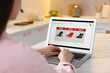 © New Africa - Woman shopping online during sale on laptop in kitchen, closeup