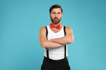 Wall Mural - Attractive man with red bow tie posing on light blue background