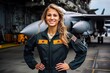 Portrait of a beautiful young woman pilot posing with hands on hips at the airfield