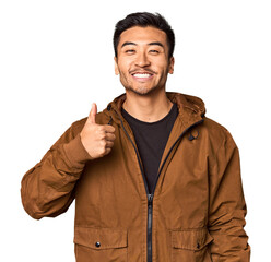 Wall Mural - Young Chinese man in studio background smiling and raising thumb up