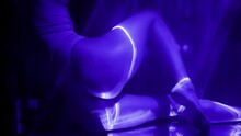 sexy ass of beautiful slender woman in darkness, purple laser rays illuminating female body