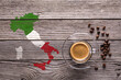 top view glass cup with espresso, some coffee beans and the shape of Italy with the colors of its flag on a gray textured wooden background.