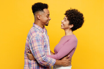 Wall Mural - Side view young happy couple two friend family man woman of African American ethnicity wearing purple casual clothes together hug cuddle embrace look to each other isolated on plain yellow background