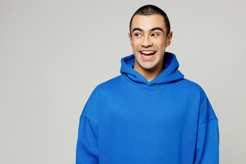 Wall Mural - Young surprised happy shocked excited amazed middle eastern man he wear blue hoody casual clothes look aside on empty area isolated on plain solid white background studio portrait. Lifestyle concept.