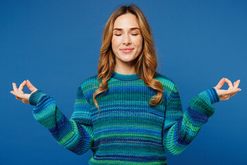 Wall Mural - Young woman she wears knitted sweater casual clothes hold spreading hands in yoga om aum gesture relax meditate try to calm down isolated on plain blue cyan color background studio. Lifestyle concept.