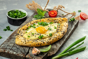 Wall Mural - Khachapuri cheese and egg filled bread on a wooden board, top view. copy space