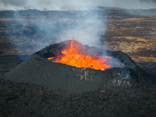 Stunning shot of dramatic moment of a volcano eruption, summit crater with boiling magma, aerial directly above view. Powerful force of nature concept.