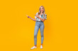 Full length photo of adorable woman wear stylish blouse denim pants indicating at discount empty space isolated on yellow color background