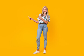 Poster - Full length photo of adorable woman wear stylish blouse denim pants indicating at discount empty space isolated on yellow color background