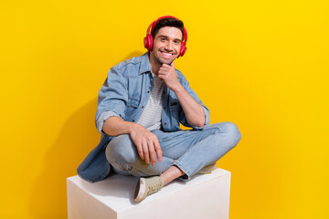 Wall Mural - Photo of dreamy cheerful man dressed jeans shirt sitting white podium enjoying songs empty space isolated yellow color background