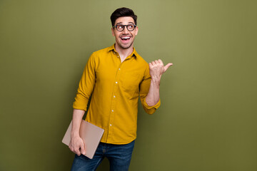 Wall Mural - Photo of positive man it specialist wear yellow trendy clothes demonstrate look offer empty space isolated on khaki color background