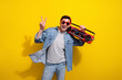 Photo of excited funky man dressed jeans shirt dark spectacles showing v-sign listening boom box songs isolated yellow color background