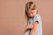 © New Africa - Suffering from allergy. Little girl scratching her arm on light brown background, space for text
