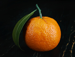 Wall Mural - Two ripe juicy tangerines on a black background.