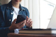 © tippapatt - Young asian business woman using mobile phone, working on laptop computer at coffee shop. Female freelancer online working, using smartphone surfing the internet, remote work, e-learning