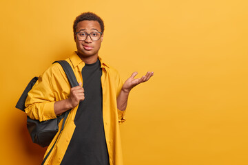 Wall Mural - People and disappointment. Studio shot of young African american male student standing on left isolated on yellow background wearing casual clothes dissatisfied with test results with blank space