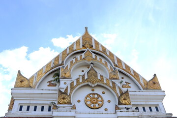 Wall Mural - White cement gable and golden painted Buddhism's symbol of Buddhism church and bright sky with clouds background in Thailand.